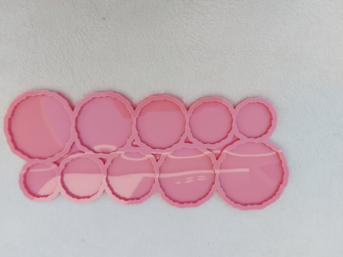 A silicone mold containing 10 interconnected circular cavities. The edges of all the circles feature a zigzag or wavy design in one piece. The cavities come in varying sizes and different diameters.