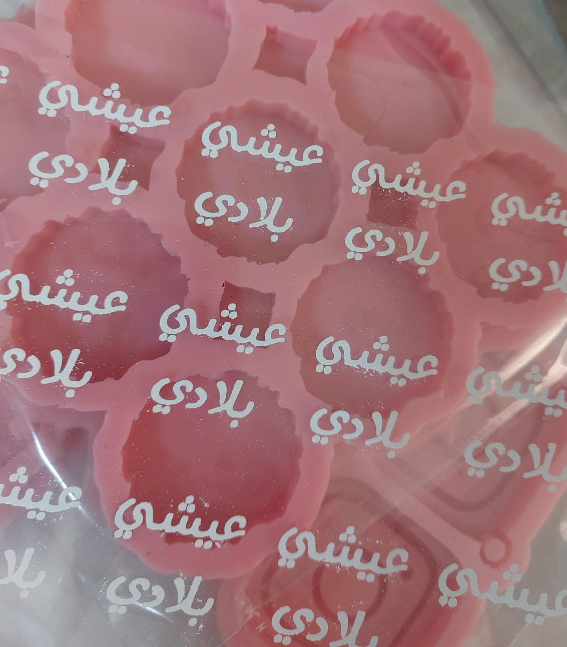 Vinyl, sticker printing, or transparent paper containing printed words in black and a simplified, modern Arabic script, suitable for crafts or resin