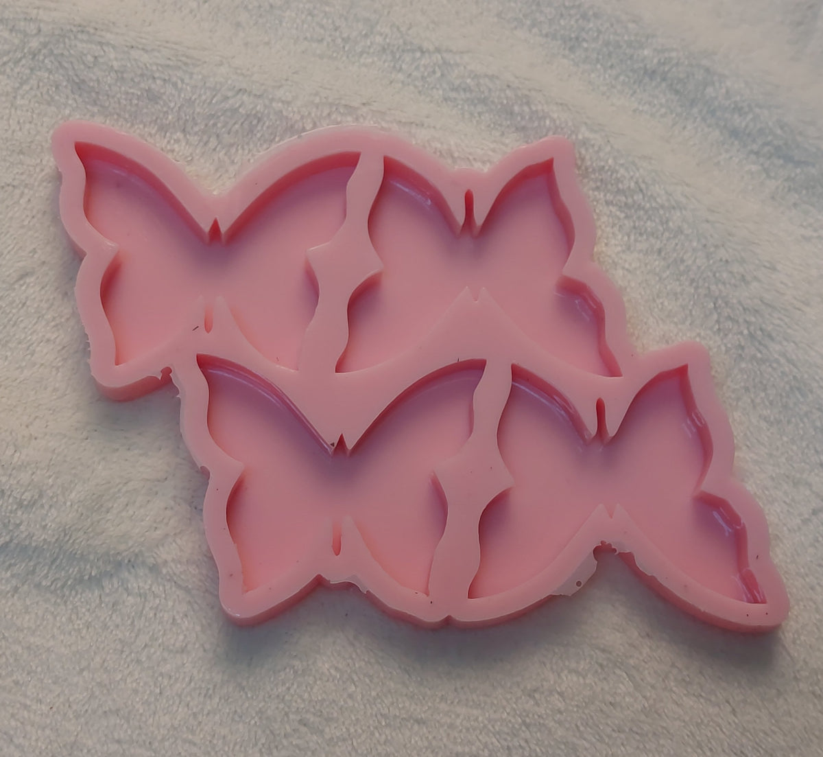A silicone mold featuring a design that combines four butterflies into a single artistic composition, suitable for making resin, wax, or ceramic medallions. Size 5