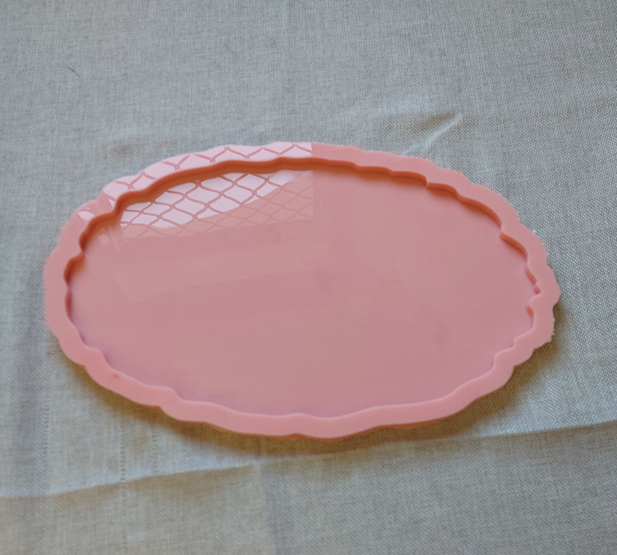 An oval silicone mold with non-straight outer and inner edges, featuring a decorative, wavy pattern resembling flower petals or regular waves. The total length of the mold is 27 cm, and the casting depth is 1 ml.