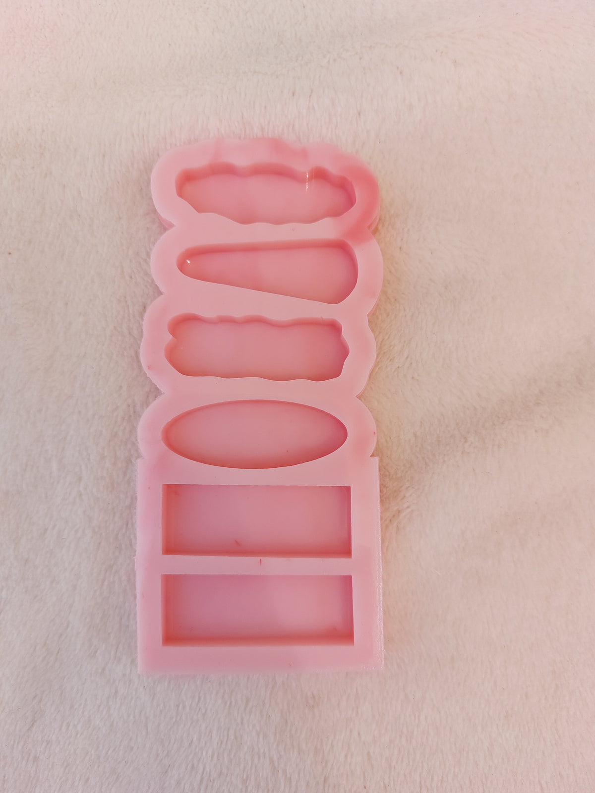 A silicone mold containing 6 elongated cavities of various shapes arranged vertically on top of each other. This mold is a common tool for casting resin or polymer clay to produce small, uniform decorative pieces. size 4*1.5cm