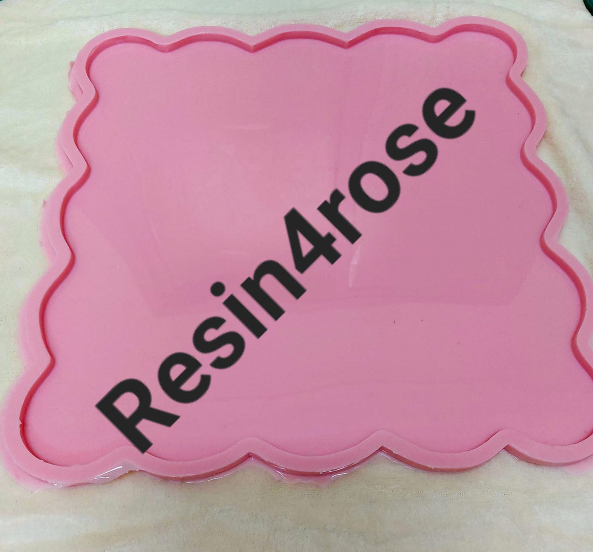 A square-shaped silicone mold with regular wavy edges, consisting of a flat inner cavity surrounded by a raised frame to define the shape and thickness of the piece. Dimensions: 27 x 27 cm, Depth: 8 mm