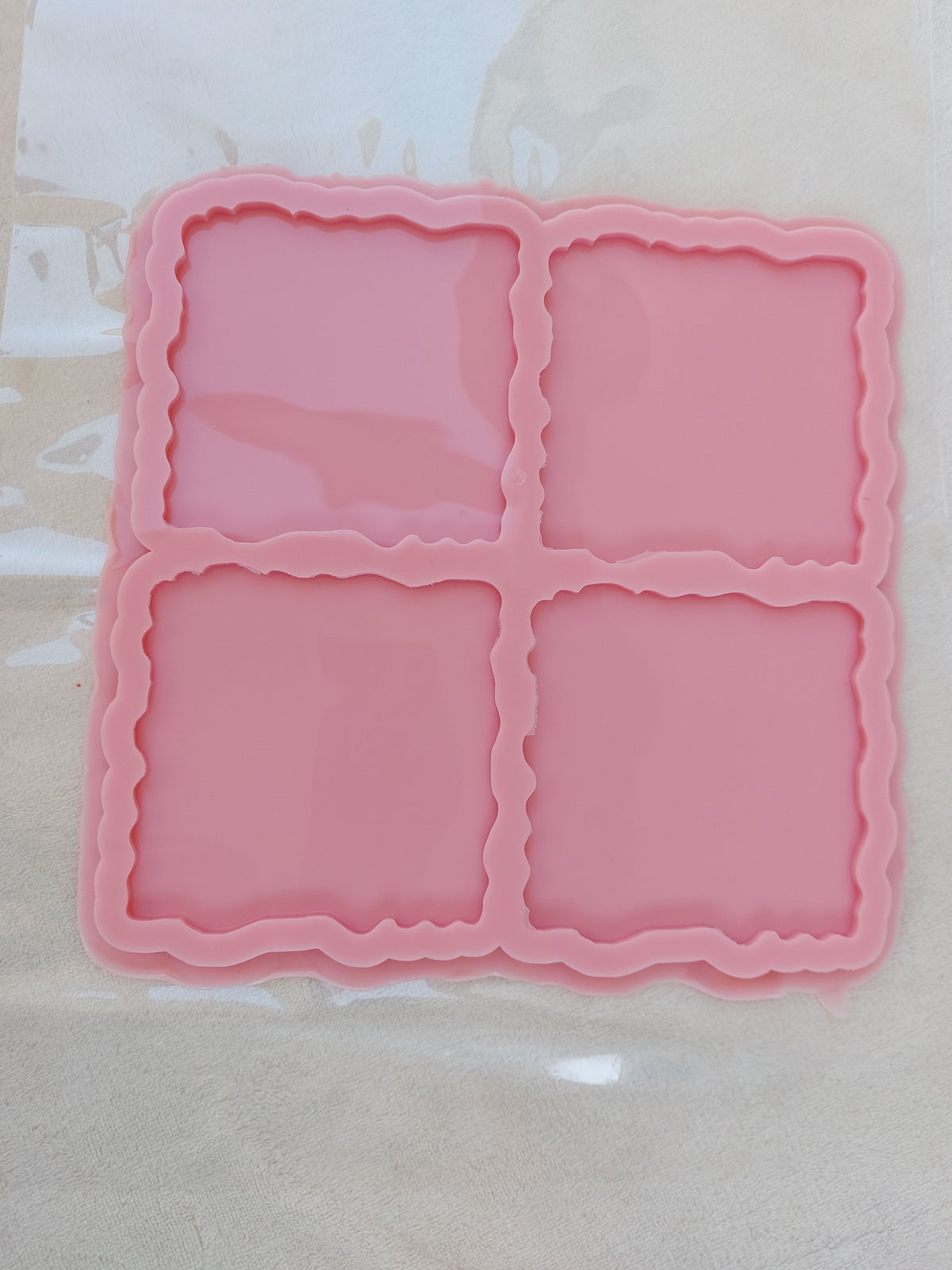 A generally square silicone mold, internally divided into four square cavities. The edges of the cavities are irregular or "wavy." Size: 15 cm Depth: 6 mm