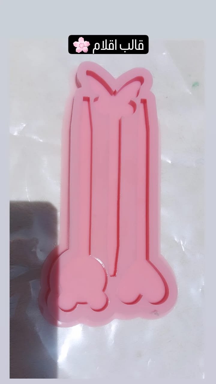 A silicone mold is a single piece containing three elongated cavities connected by decorative shapes at their ends, used for making pens, and for casting resin, wax, or pottery.