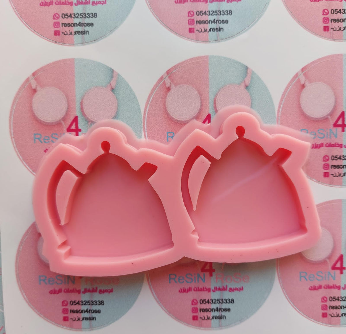 This silicone mold has two interconnected cavities, each designed in the shape of a teapot. This mold allows you to produce multiple identical pieces simultaneously with a small amount of material. Dimensions: 5 x 5 cm, Depth: 8 mm