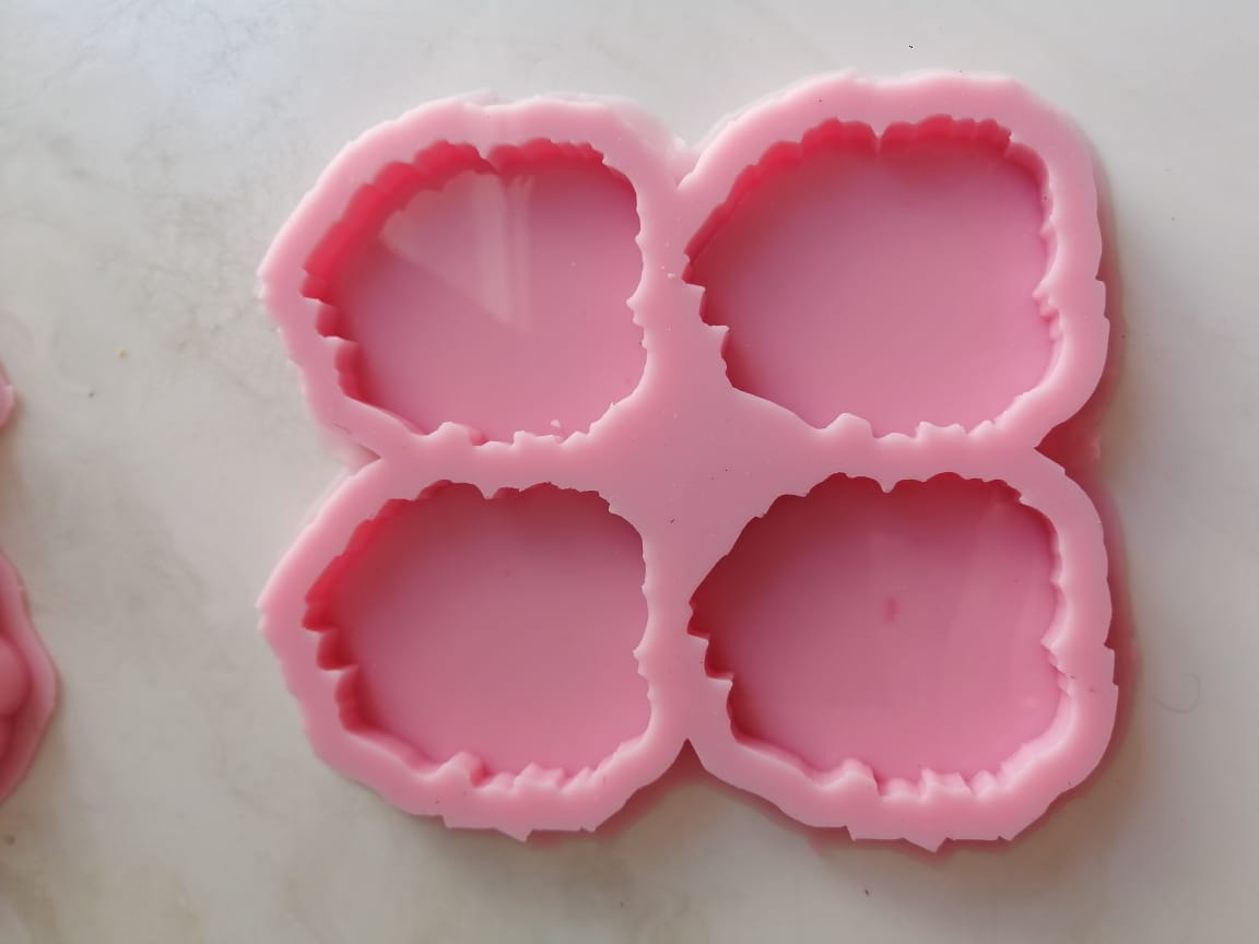 A silicone mold with four nearly circular cavities,High quality but featuring irregular, wavy edges, used to make artistic keychains, pendants, or even small pieces to decorate wall art or create decorative pieces resembling gemstones