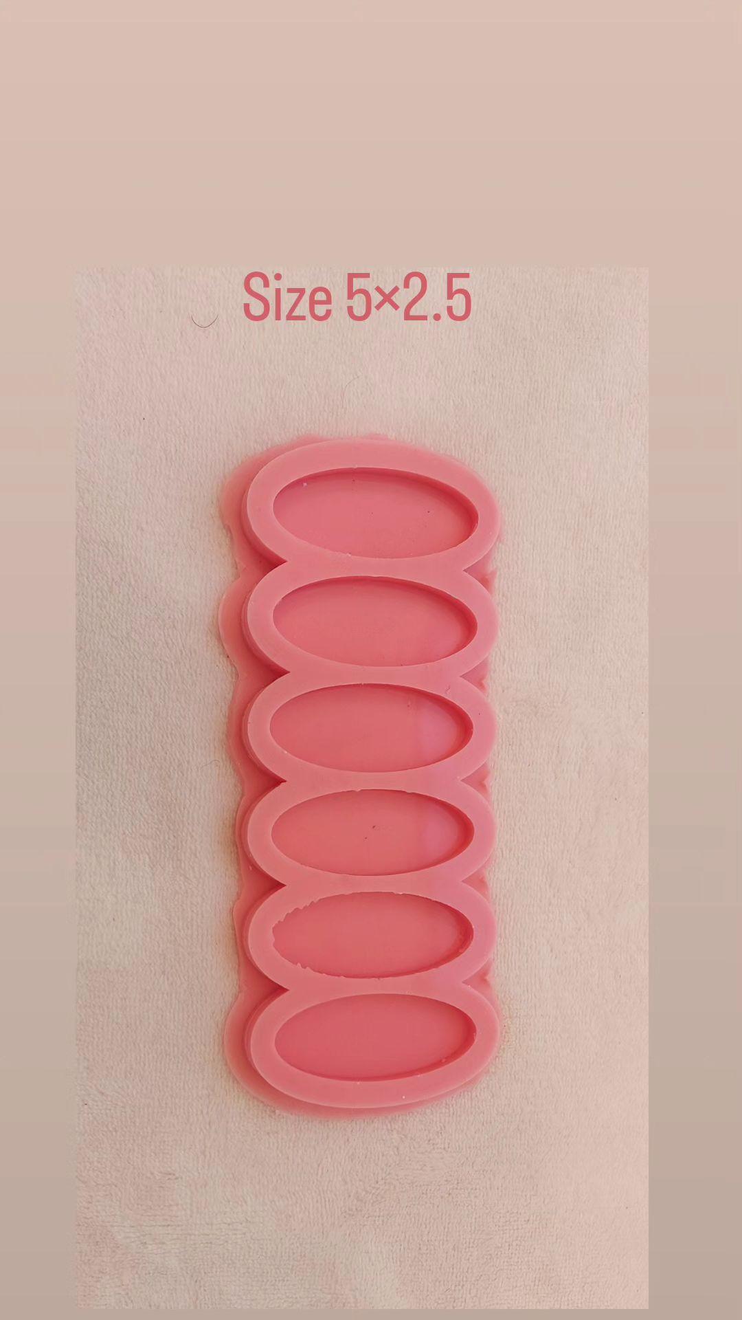 This silicone mold has six vertically aligned, elongated cavities. It is a common tool for casting resin or polymer clay to produce small, uniform decorative pieces. Dimensions: 2.5 x 5 cm, Depth: 6 mm