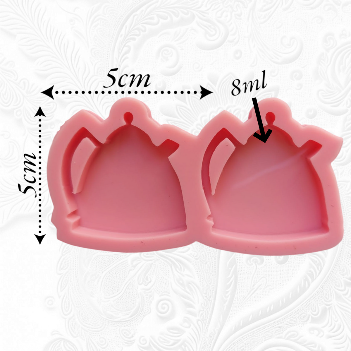 This silicone mold has two interconnected cavities, each designed in the shape of a teapot. This mold allows you to produce multiple identical pieces simultaneously with a small amount of material. Dimensions: 5 x 5 cm, Depth: 8 mm