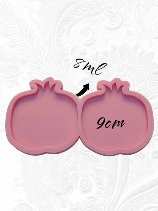 A silicone mold specially designed for crafting projects such as casting resin, polymer clay, wax, or pottery. The mold consists of two connected cavities shaped like a pomegranate, measuring 9 cm in length and 8 mm in depth.