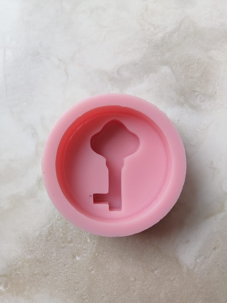 A round silicone mold with a raised key, suitable for making resin, candle, or concrete pendants, scented soaps, and fragrant mastic.