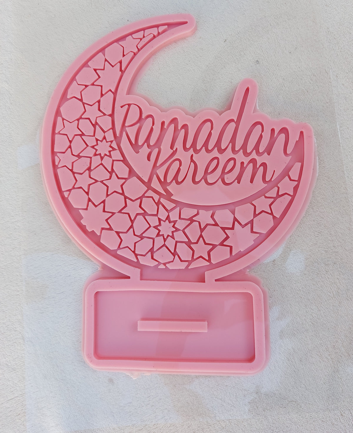 This silicone mold is suitable for casting resin, wax, or ceramics. Inside the circle is the phrase "Ramadan Kareem" in an intricate and beautiful design, clearly depicting domes, minarets, and pointed architectural motifs.