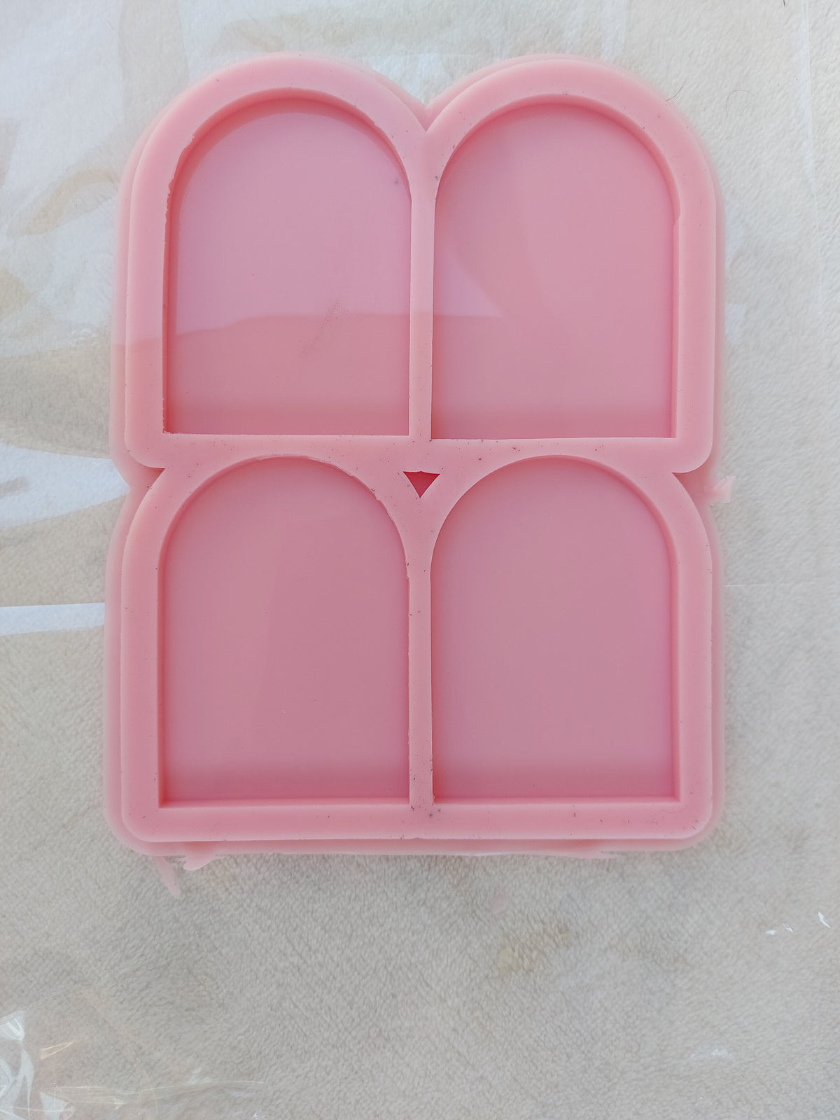 This silicone mold contains four identical cavities in size and shape.  Each cavity takes the form of an "arch" or "niche," featuring a straight base and vertical sides that culminate in a semi-circular curve at the top. Dimensions: 5 x 7 mm, Depth: 6 mm