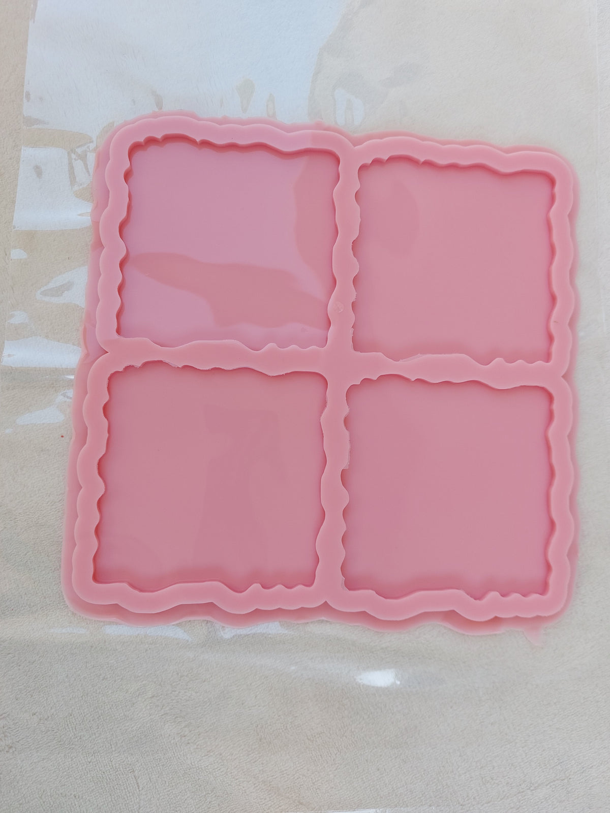 A generally square silicone mold, internally divided into four square cavities. The edges of the cavities are irregular or "wavy." Size: 15 cm Depth: 6 mm