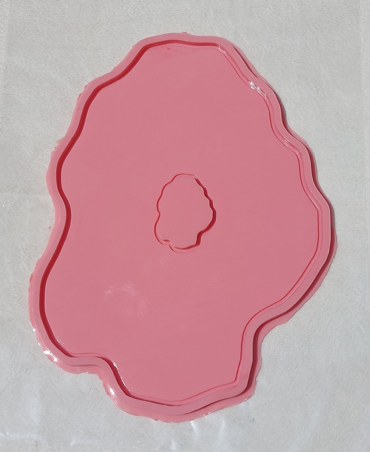 This silicone mold features an irregular, organic design that mimics the wavy edges of natural gemstones or stone slabs. It has a wide, flat main cavity with a small, irregularly shaped protrusion in the center.