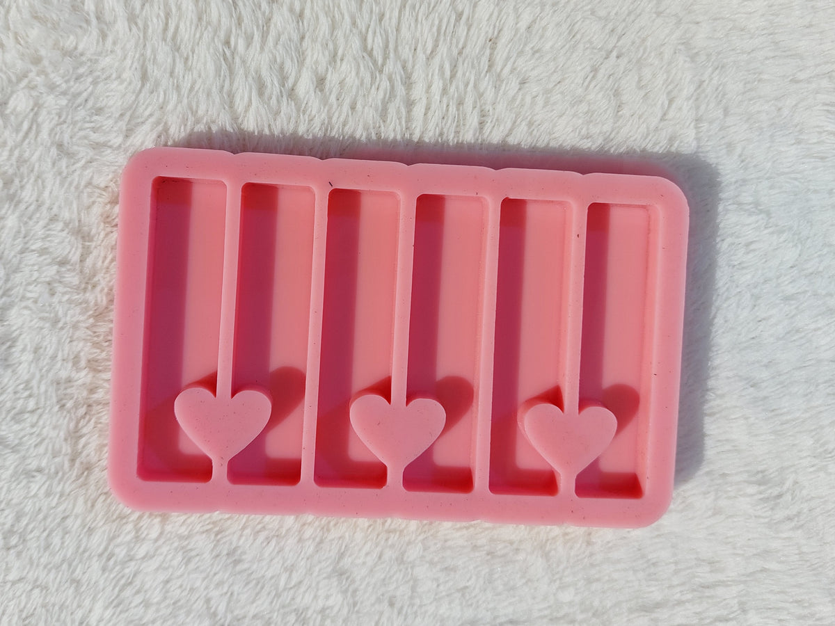 A rectangular silicone mold with multiple, organized cavities and a heart-shaped opening connecting each pair of adjacent rectangles, designed for casting resin, wax, or plaster. Dimensions: 3.3 x 6 cm.