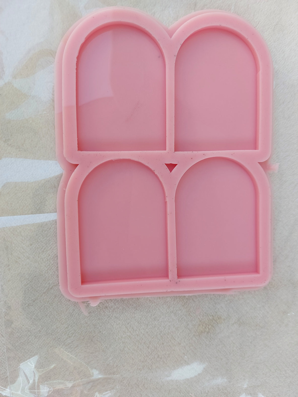 This silicone mold contains four identical cavities in size and shape.  Each cavity takes the form of an "arch" or "niche," featuring a straight base and vertical sides that culminate in a semi-circular curve at the top. Dimensions: 5 x 7 mm, Depth: 6 mm
